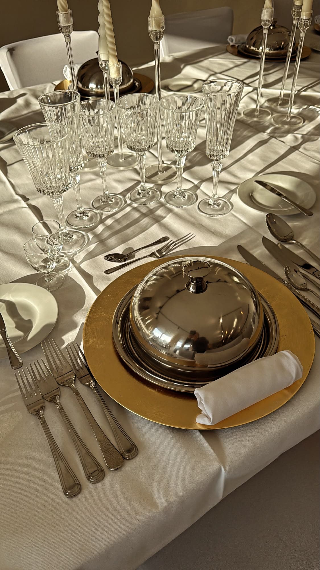 Gedeckter Platz mit Cloche und goldenem Platzteller im Abendlicht — Knigge-Seminar in Krefeld-Uerdingen
