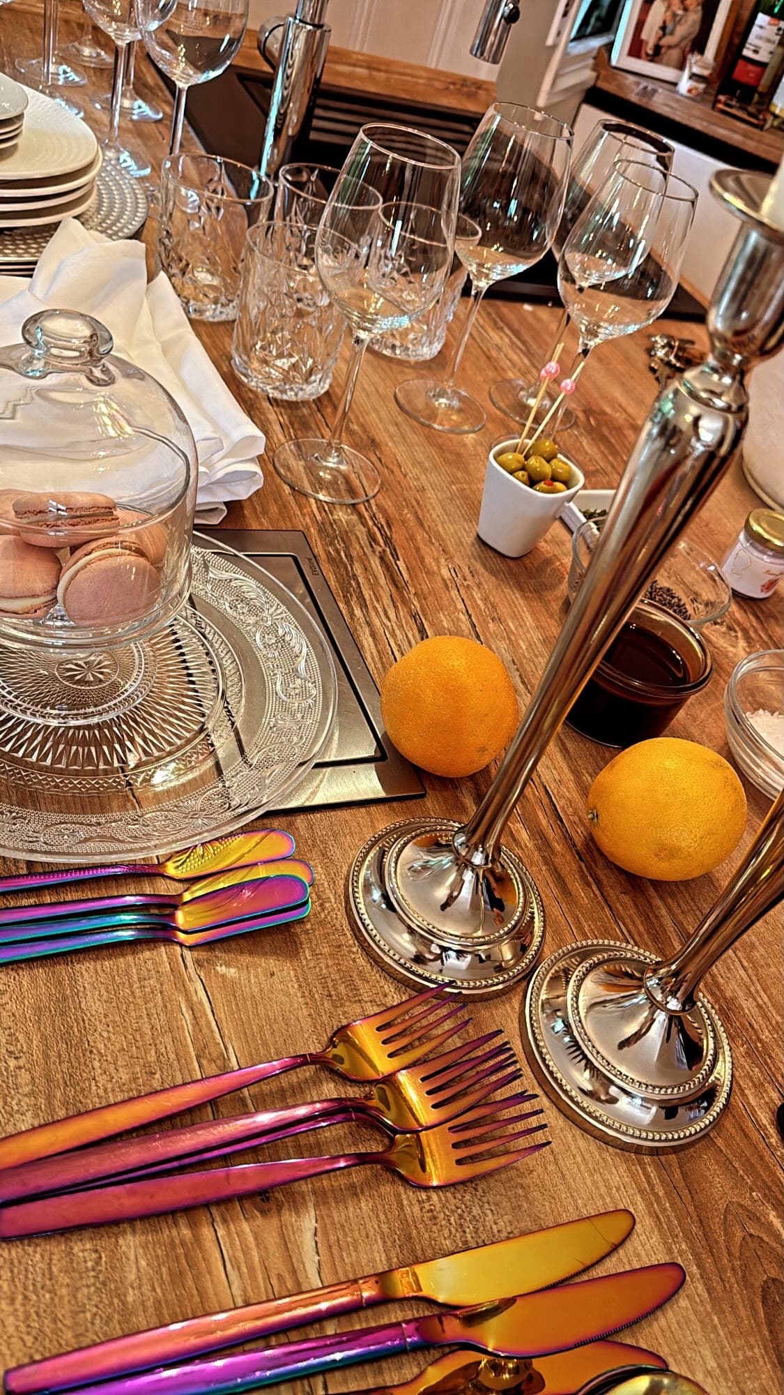 Vorbereitete Tafel mit Macarons, Kerzenleuchtern und Regenbogen-Besteck